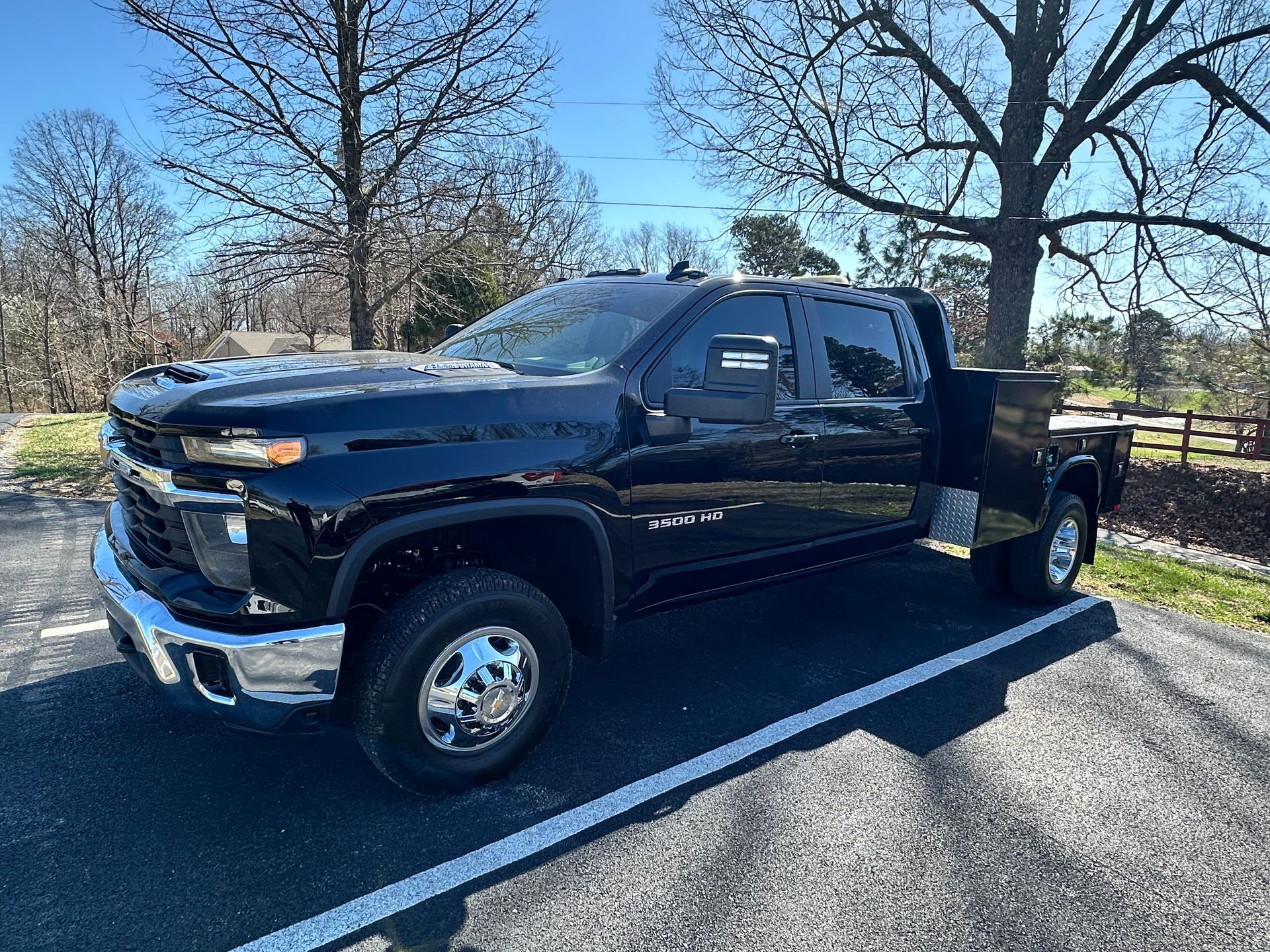 Black Chevrolet Silverado 3500 dually truck parked outside on a sunny day.