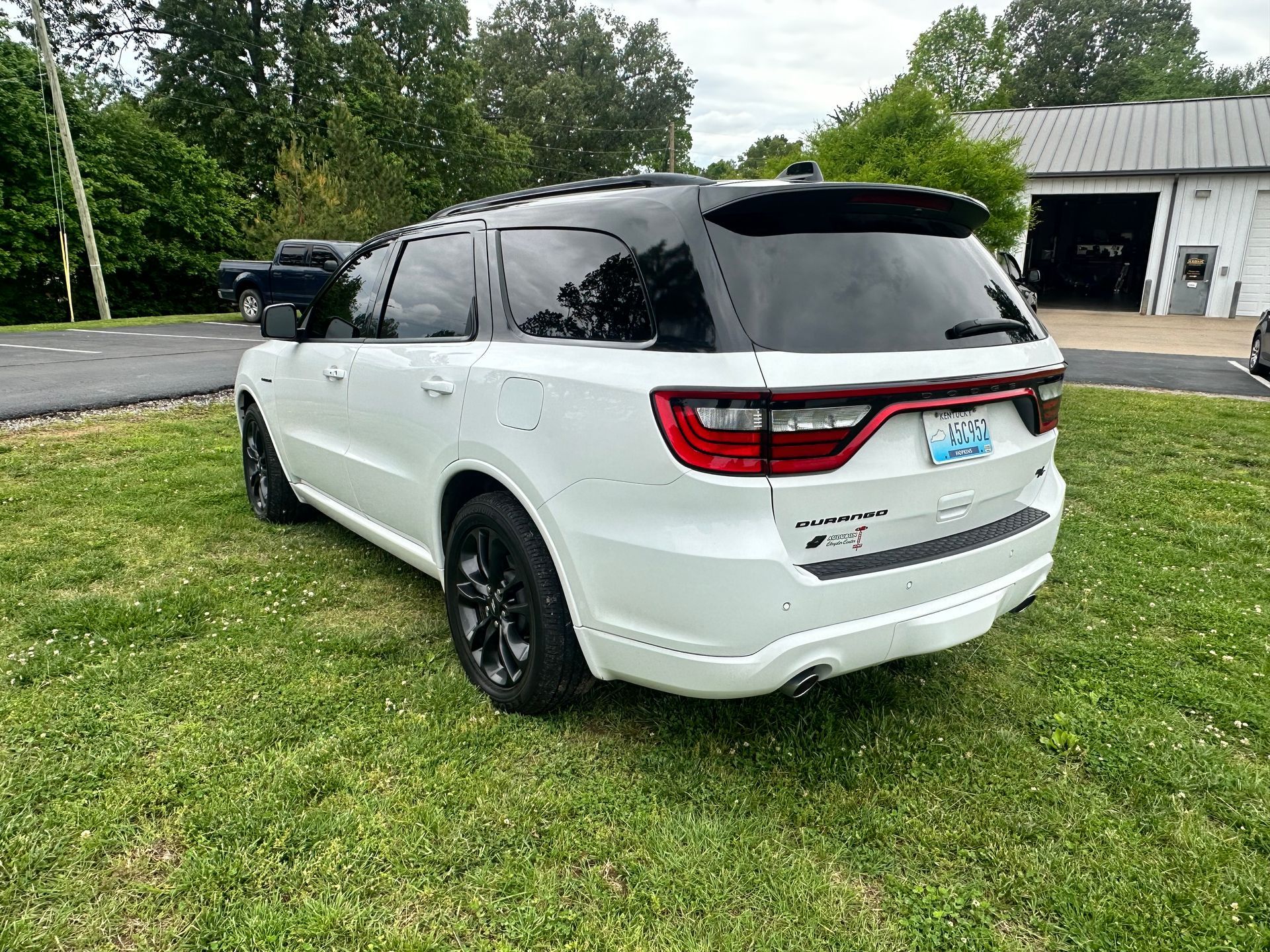 White Dodge Durango SUV with black accents parked on grass near a building.