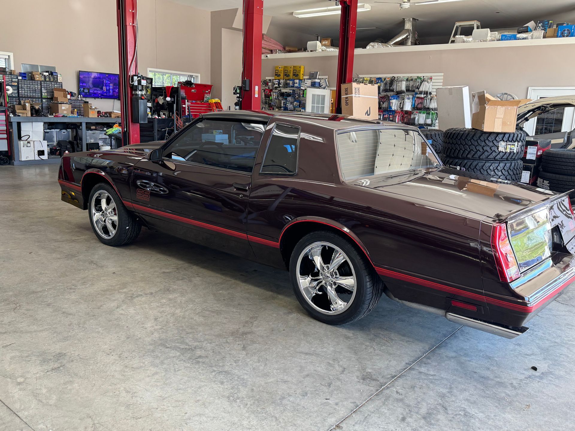 Dark brown classic car with red trim parked in an auto repair shop.