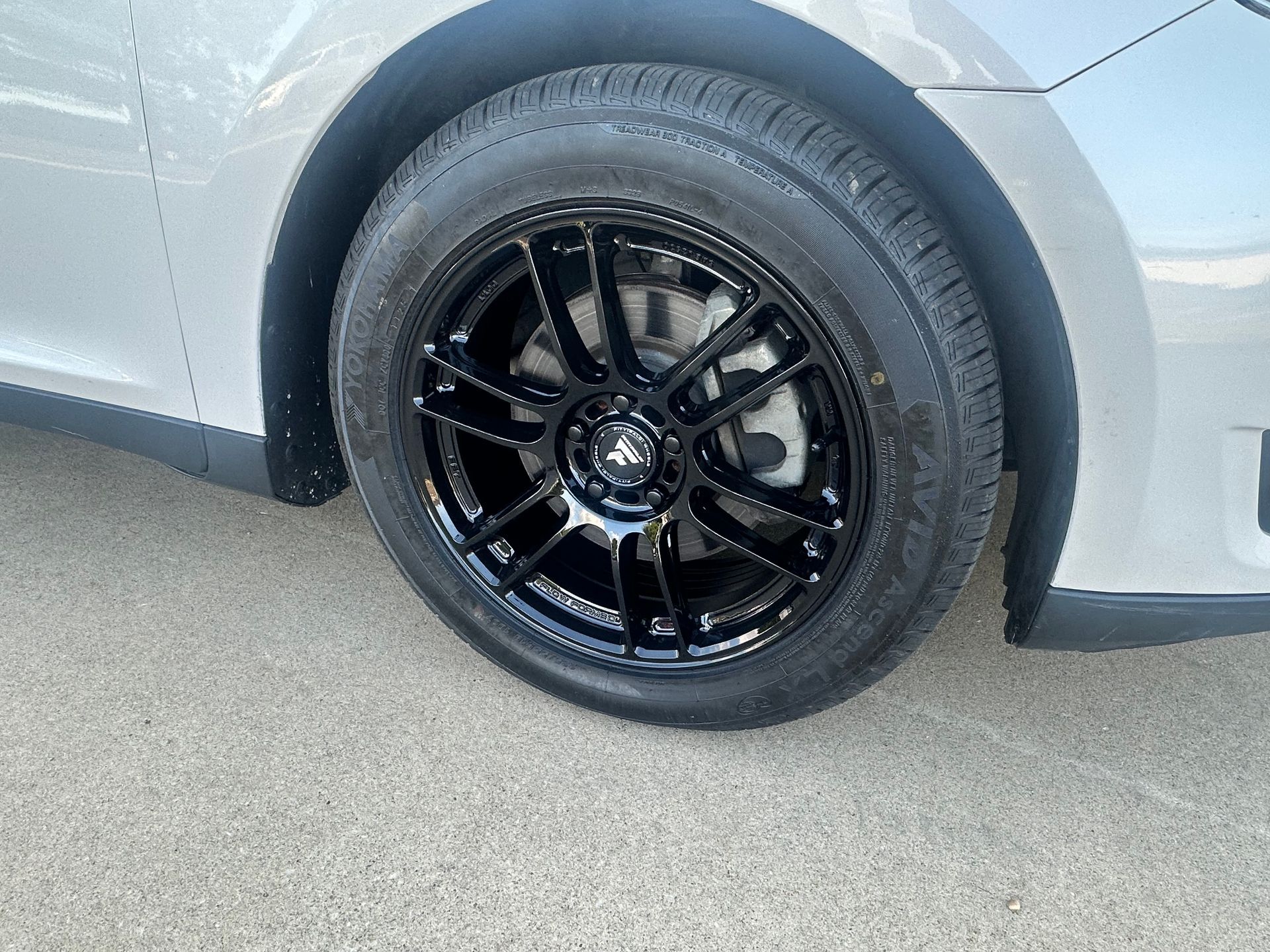 Black car wheel on gray pavement.