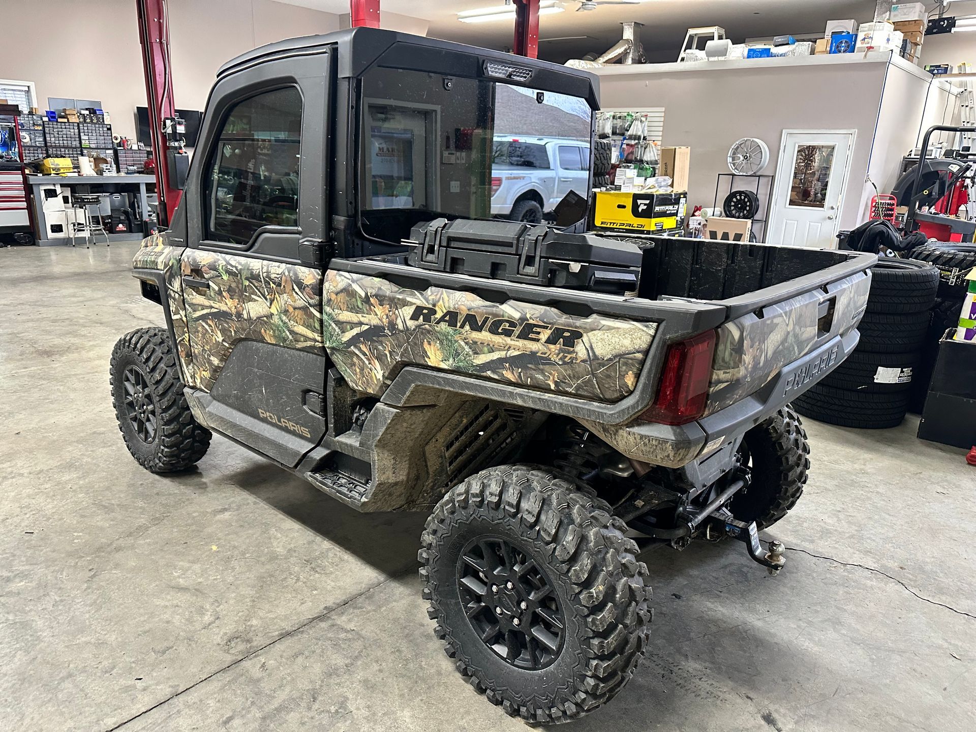Camouflage Ranger utility vehicle with black wheels and canopy, indoors.