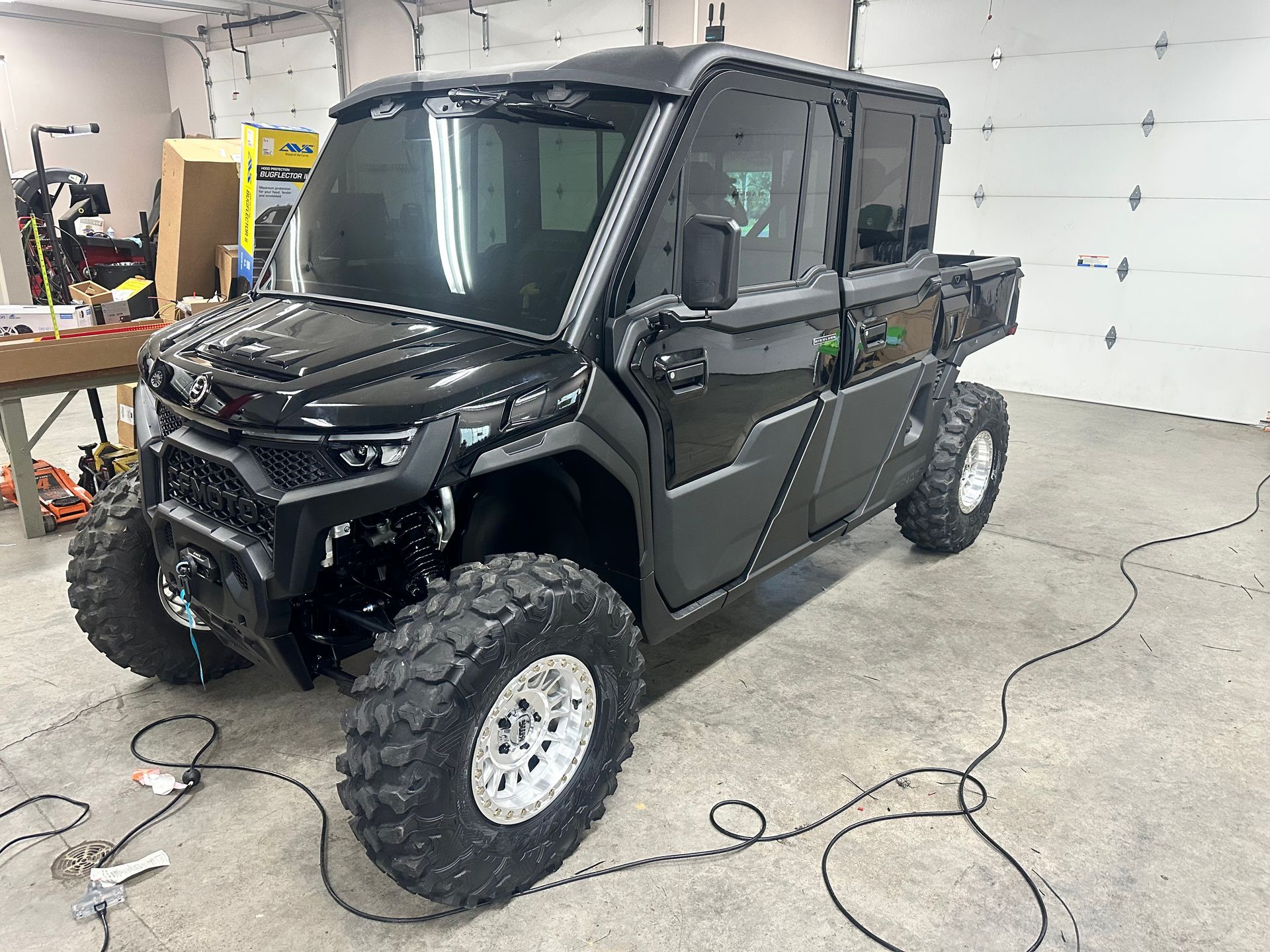 Black UTV with tinted windows and large off-road tires, parked in a garage.