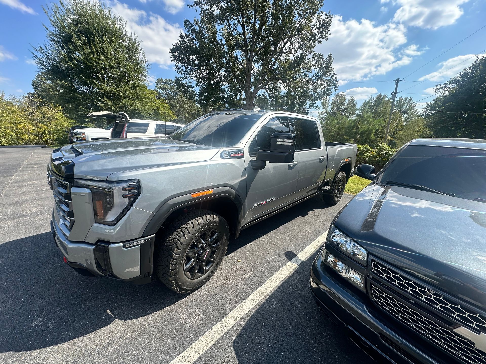 Gray GMC truck parked outdoors on a sunny day next to a black Chevy truck.