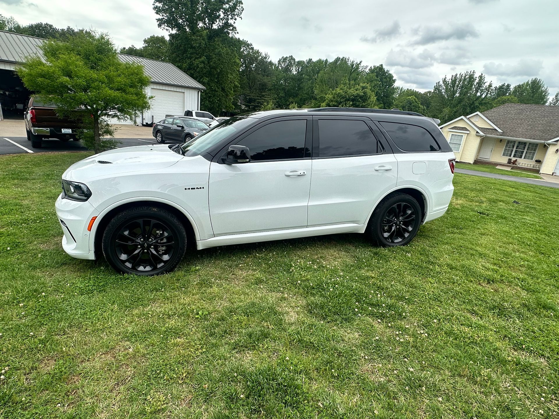 White Dodge Durango SUV with black wheels and tinted windows parked on grass.