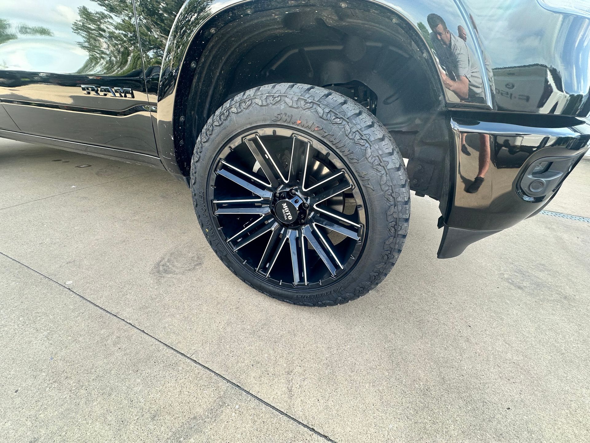 Black truck wheel with black and silver rims on pavement.