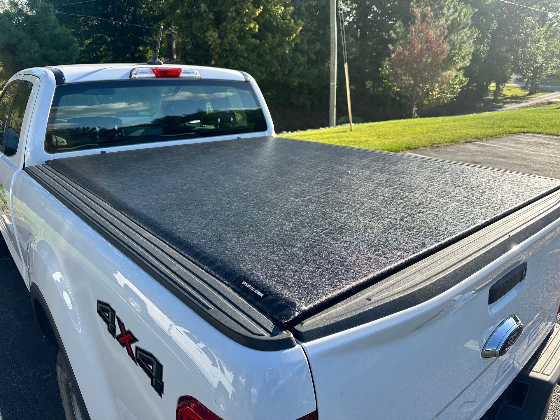 White pickup truck with a closed black tonneau cover, parked outdoors.