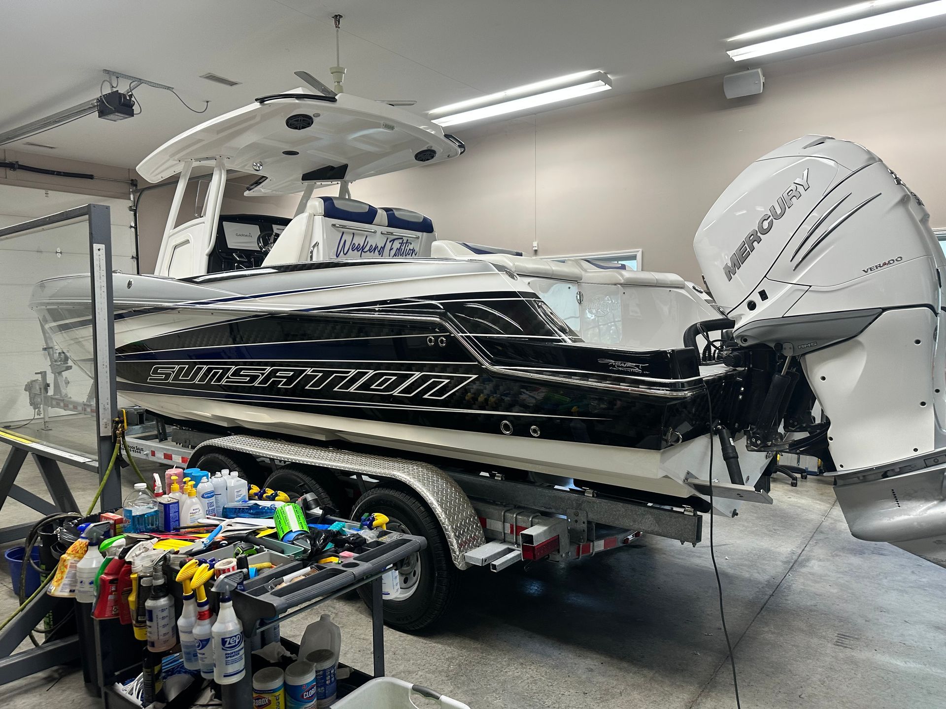 A large white and black motorboat on a trailer inside a workshop.