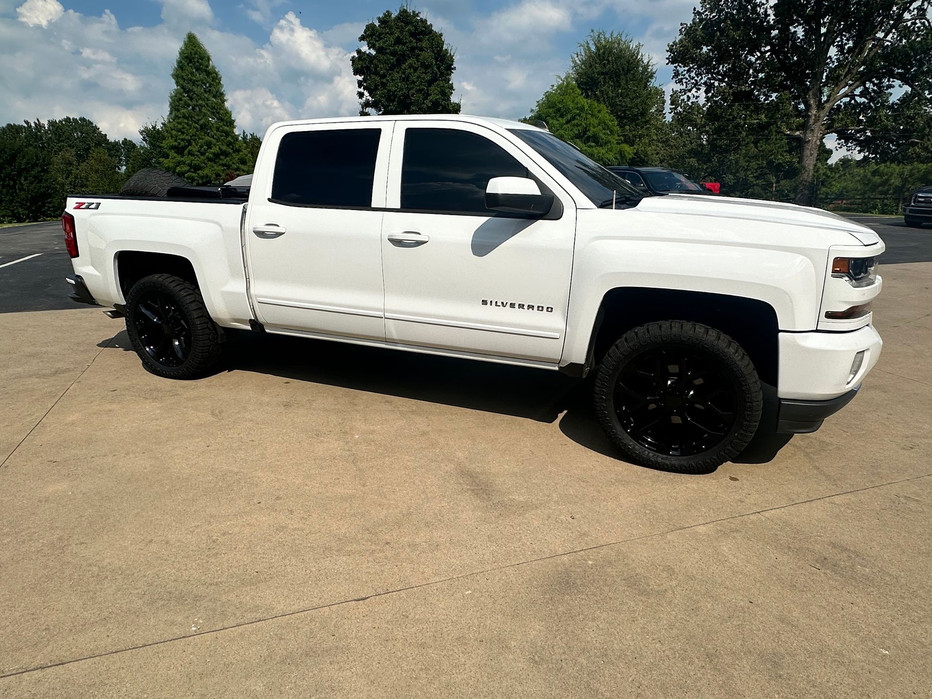White pickup truck with black wheels and tinted windows parked outside on a sunny day.