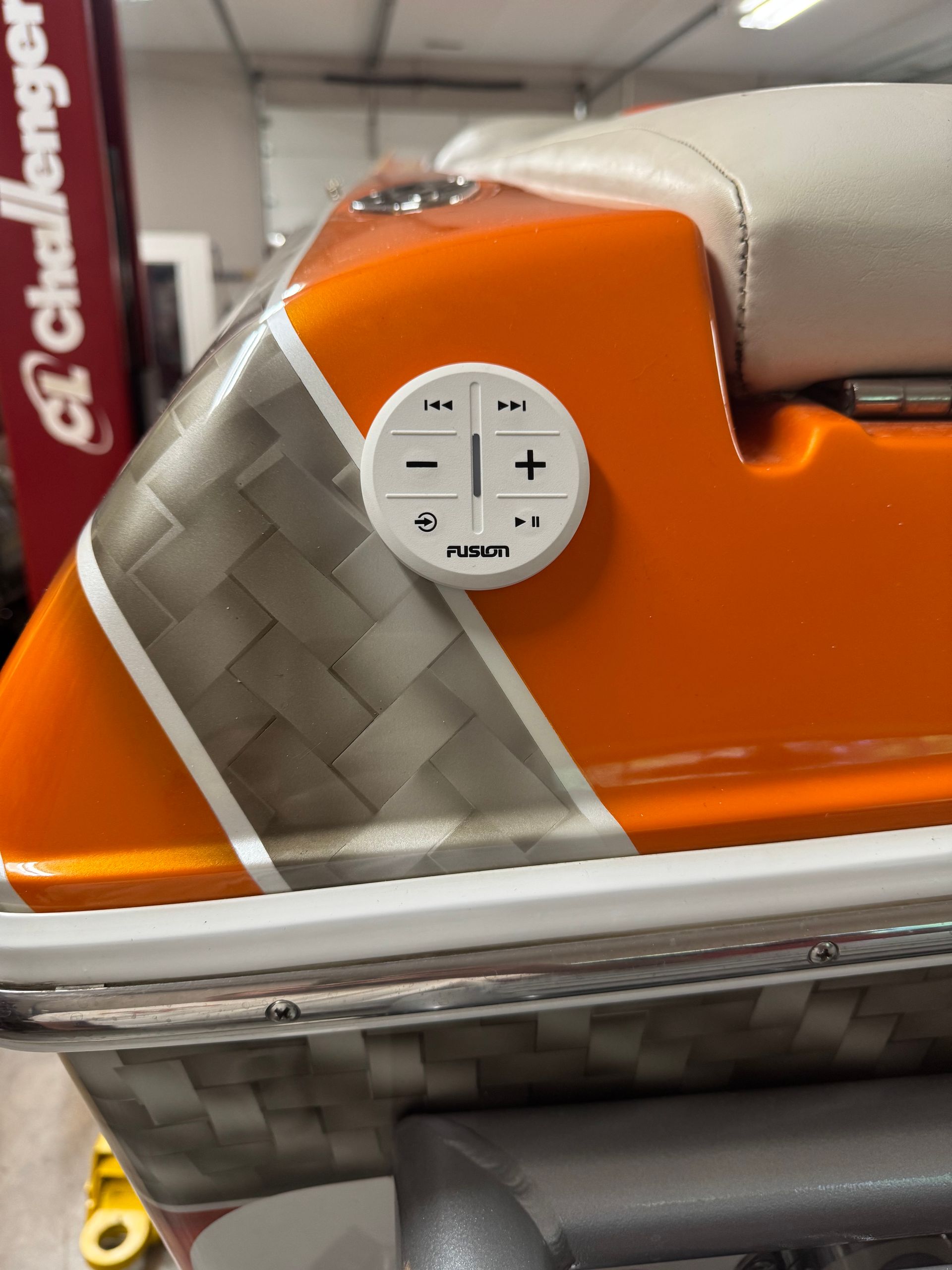 Orange and gray boat with white control panel featuring volume and track controls.