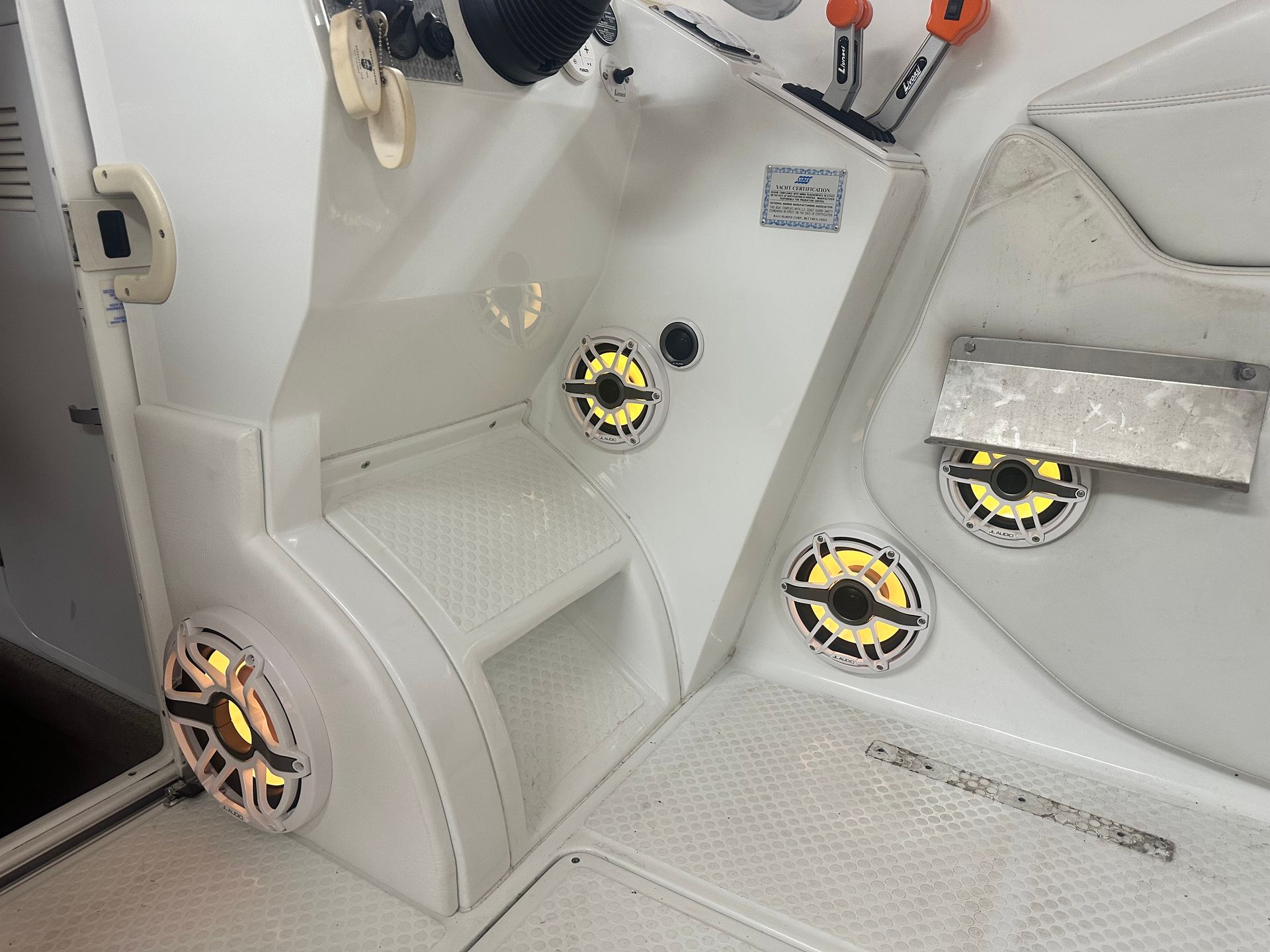White boat interior with speakers, a control panel, and steering wheel.