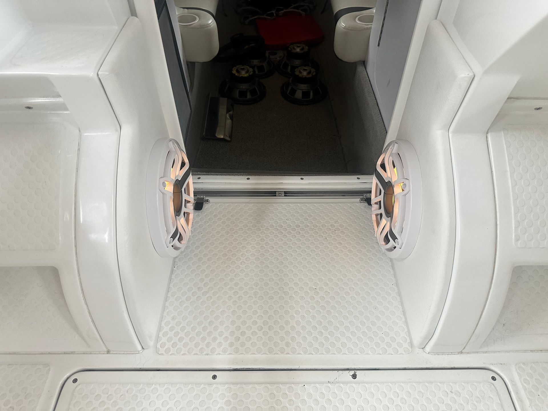 White boat interior with speakers, flooring, and seating area visible.