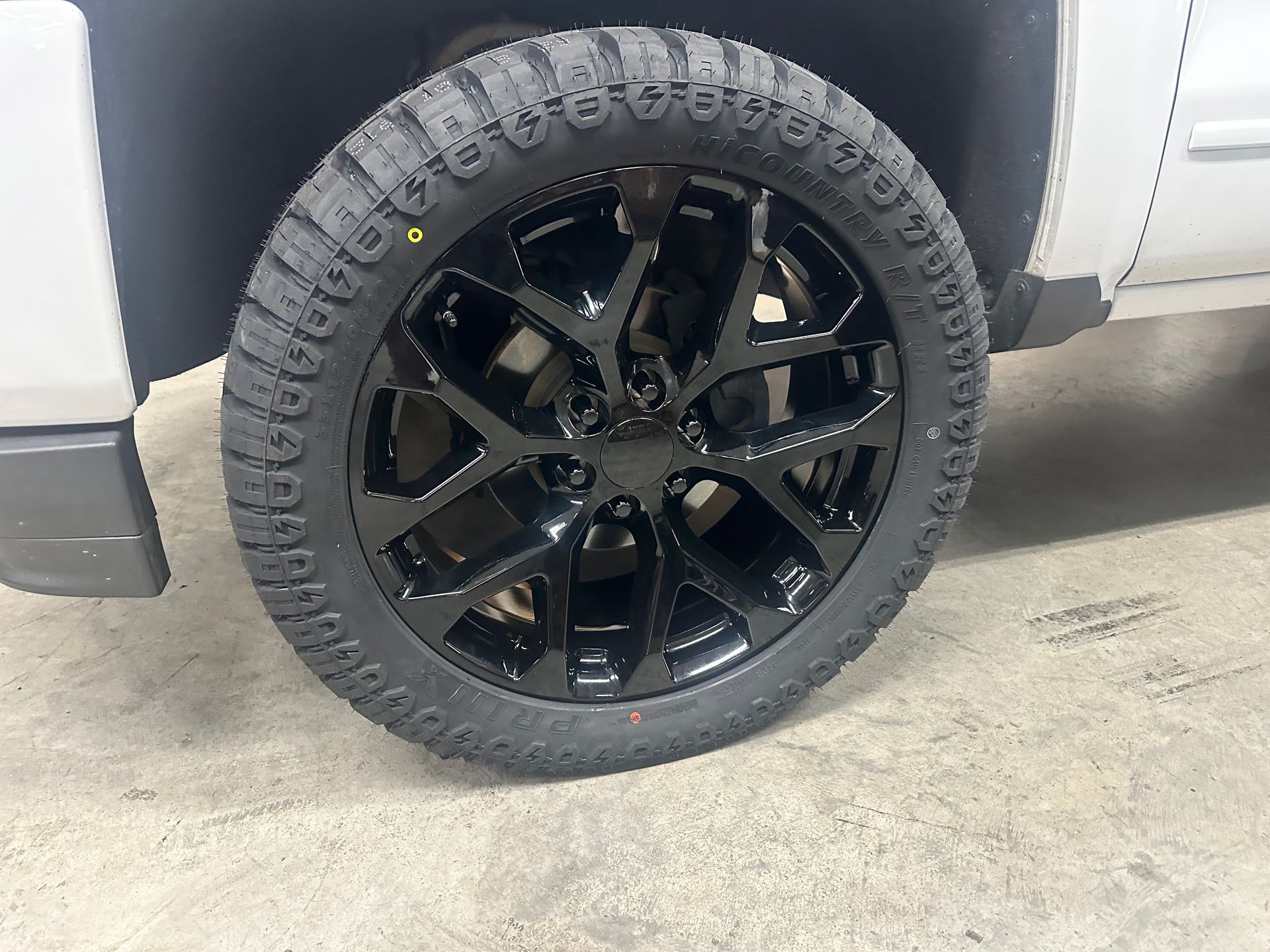 Black alloy wheel with textured tire on a silver truck.