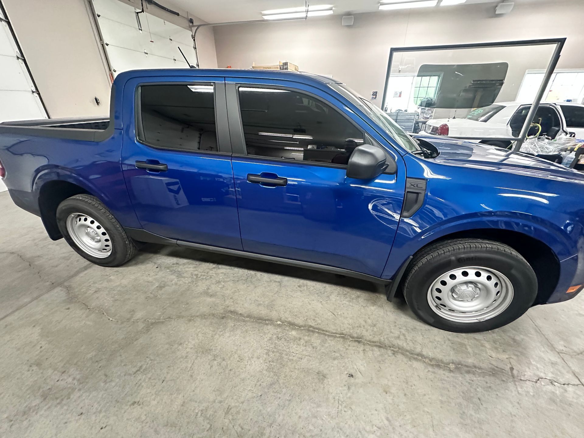 Blue pickup truck parked inside a garage, next to a window.