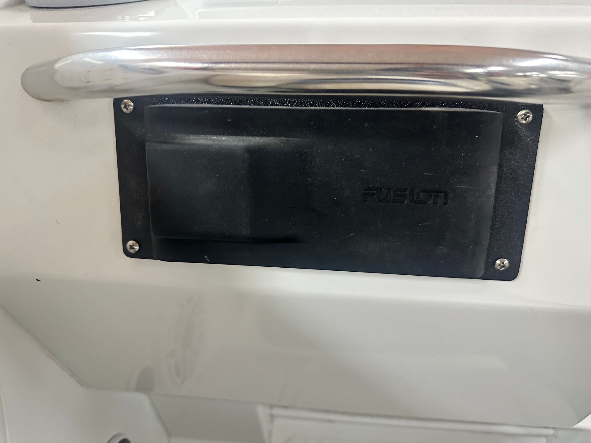 Black Fusion marine stereo remote control mounted on a white boat.