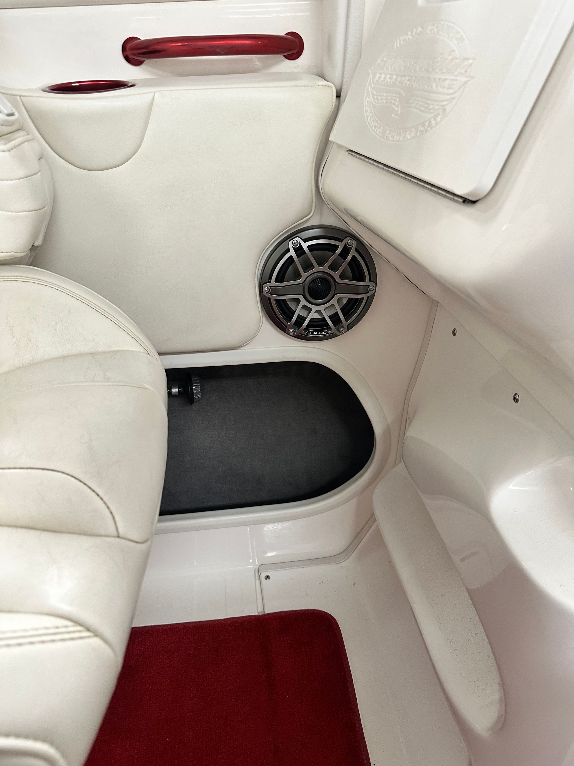 Interior of a white boat with a speaker, red handle, and red carpet.