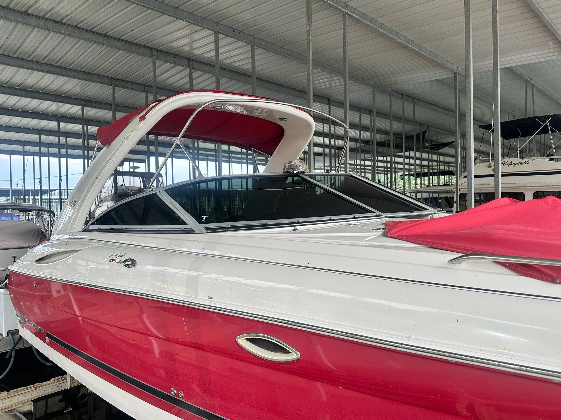 Red and white motorboat under a shelter with a red canopy.