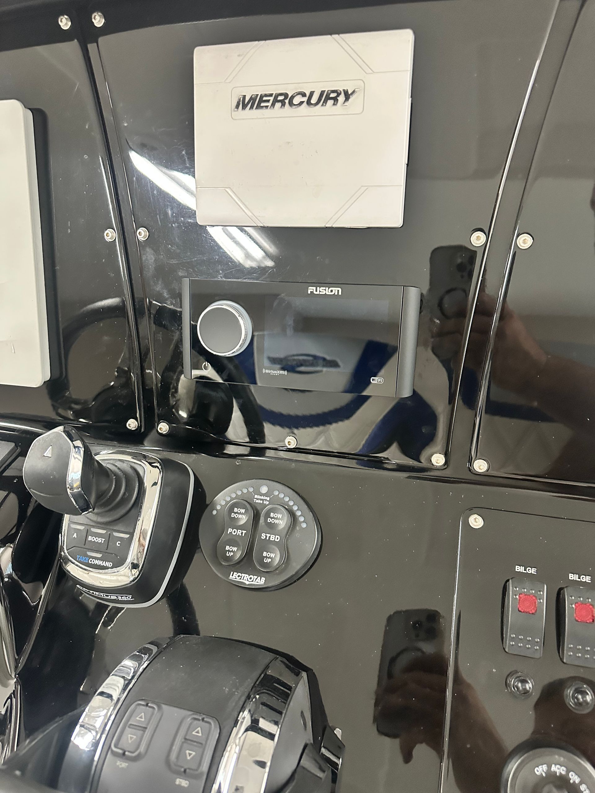 Boat dashboard with Mercury display, joystick, and various controls. Black and silver.