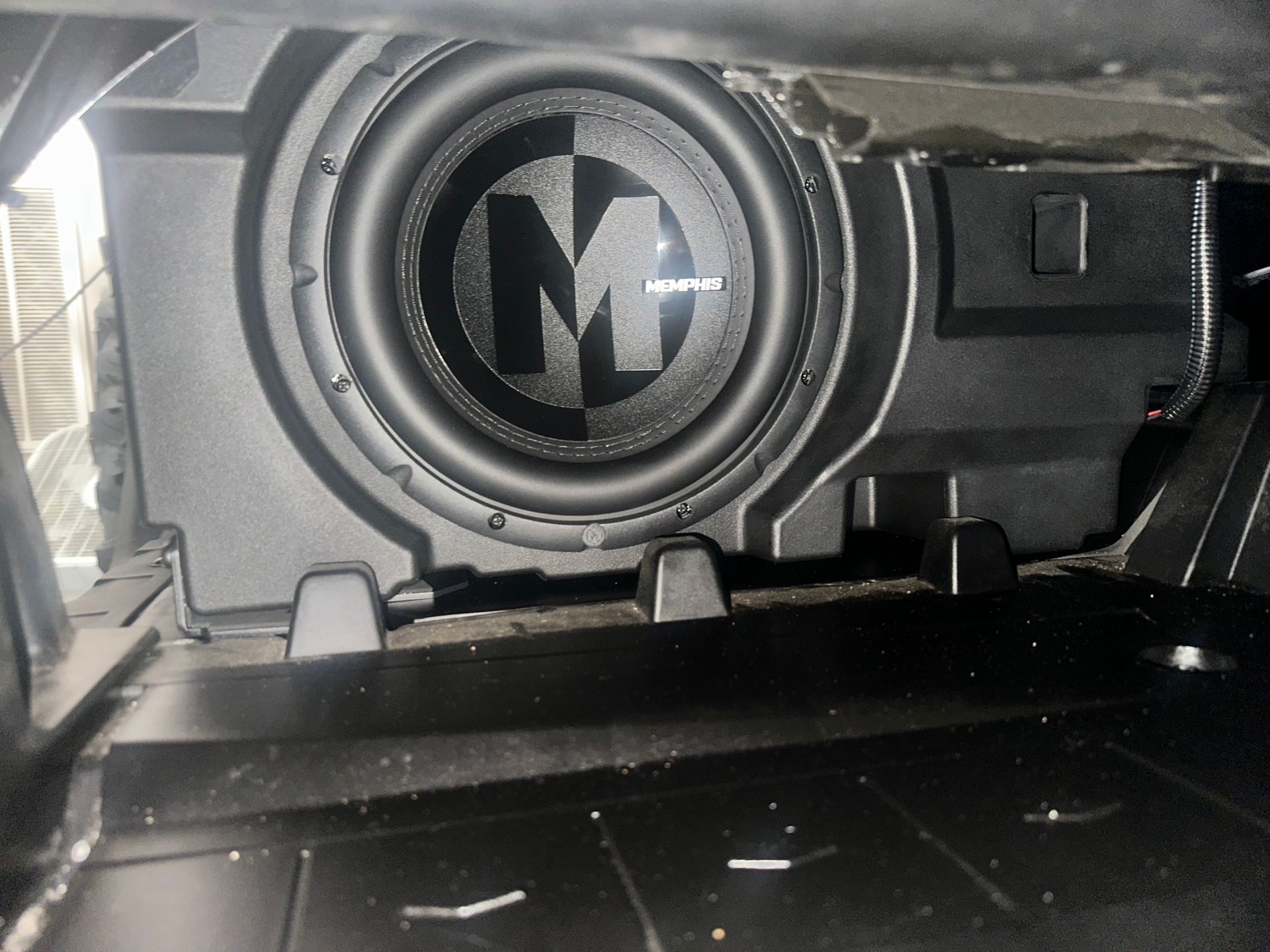 Black subwoofer installed in a car trunk, with the