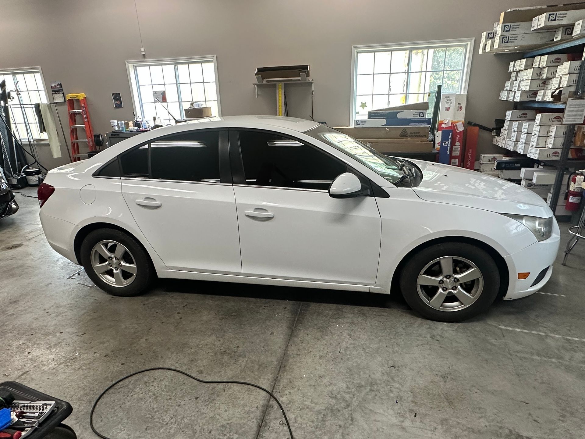 White sedan with tinted windows in a shop setting.