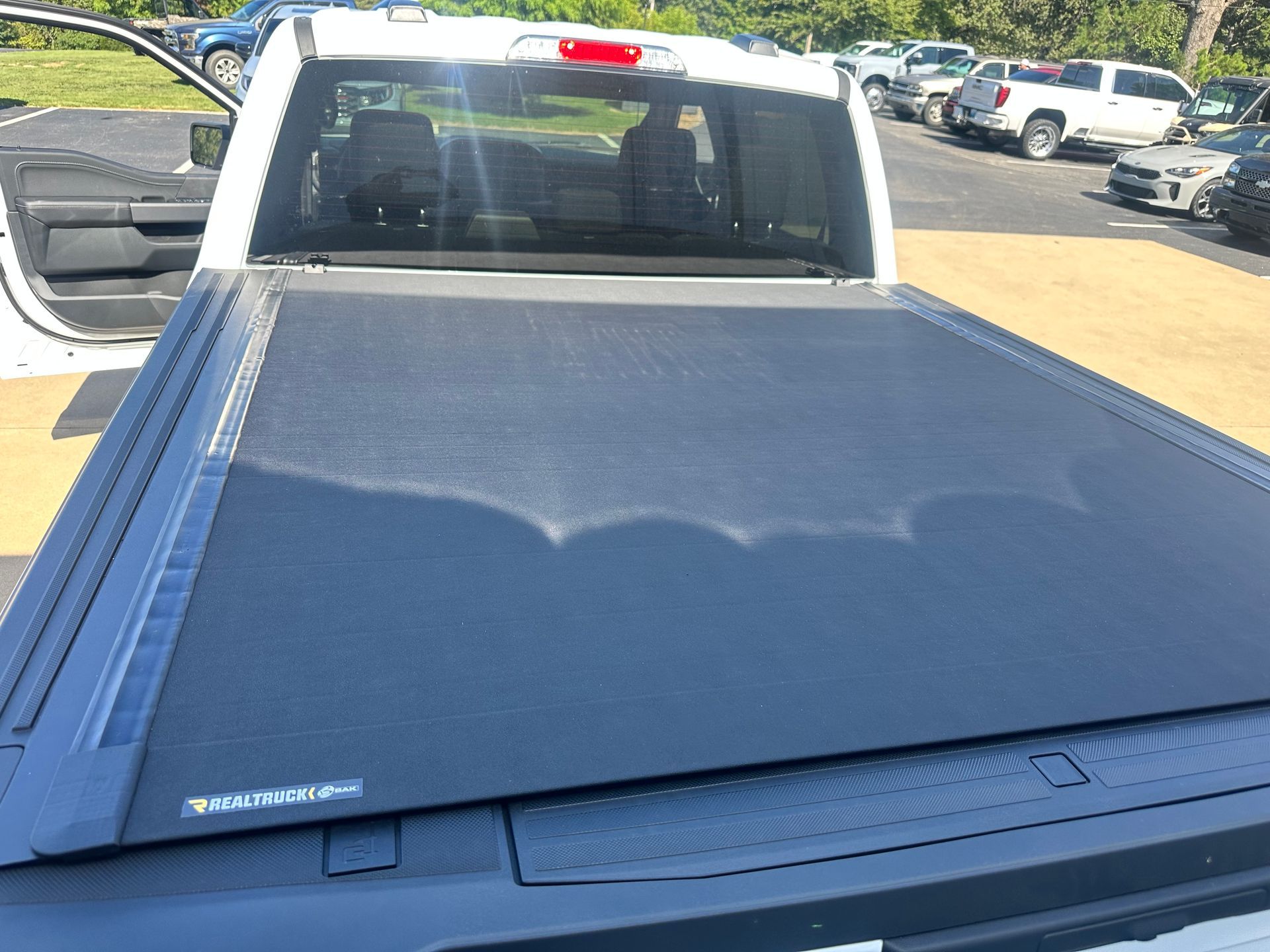 A black truck bed cover on a white pickup truck.