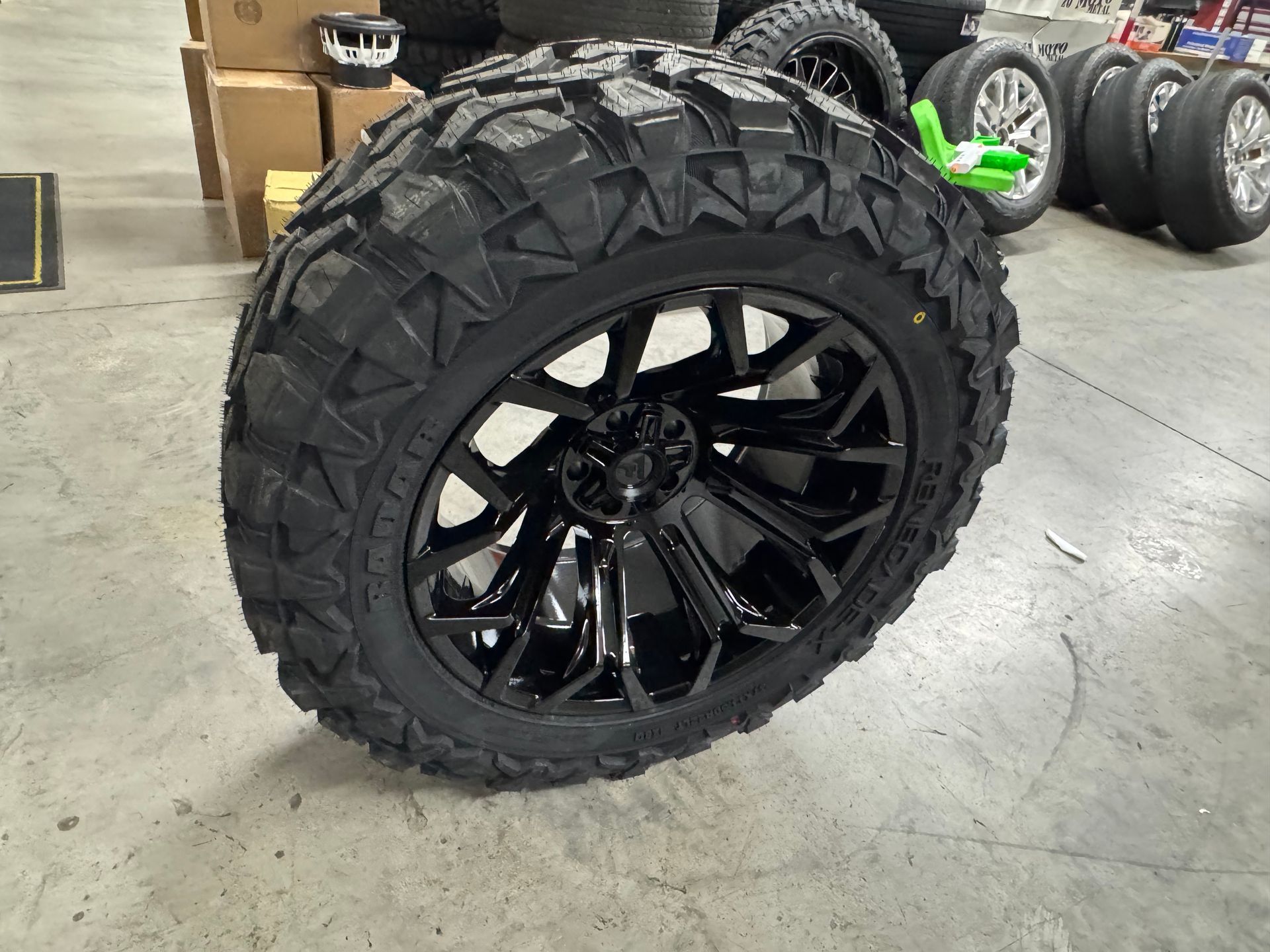 Black tire with deep treads and black rim, indoors.