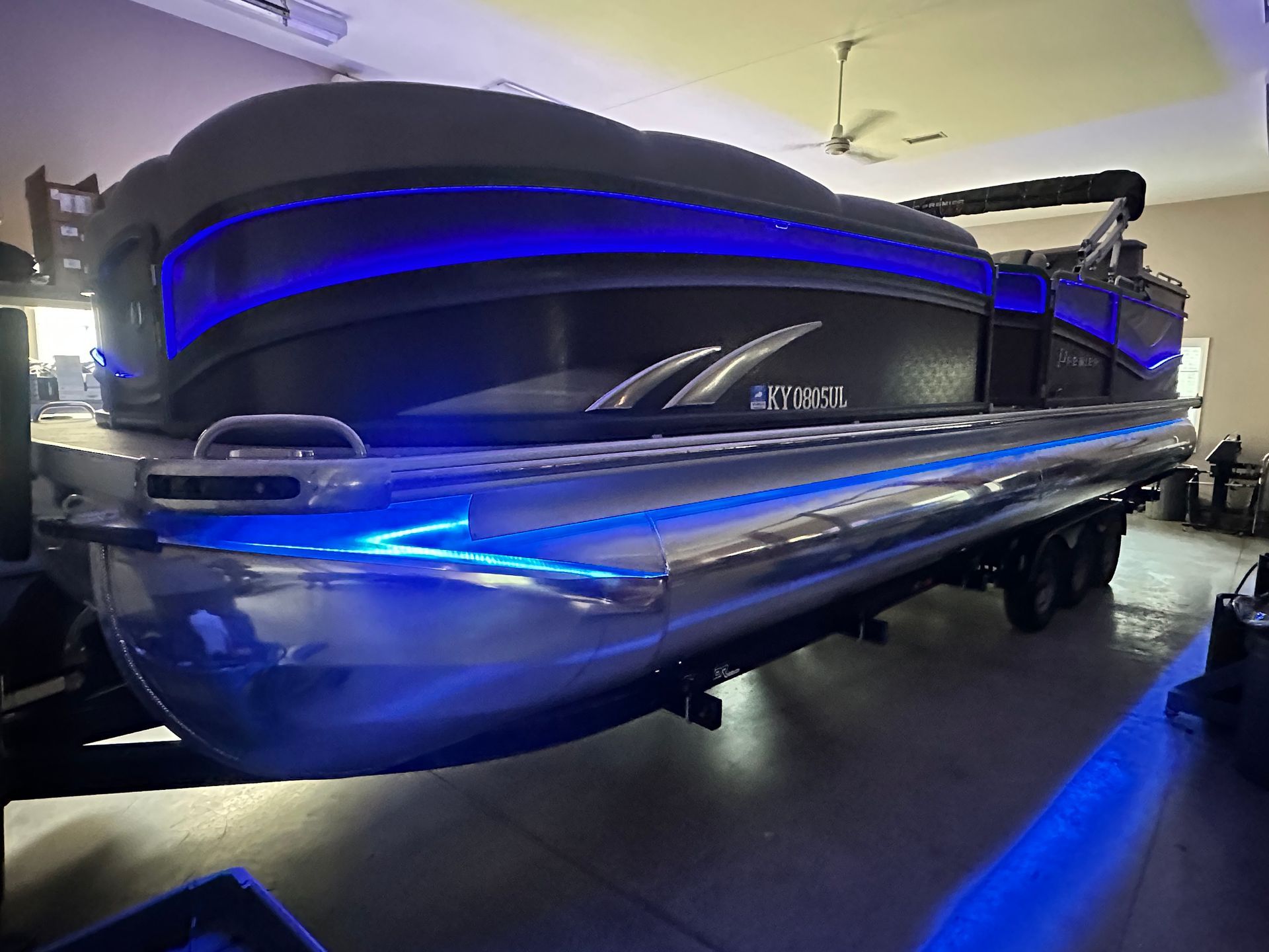 Pontoon boat with blue LED lights, black and chrome exterior, indoors.