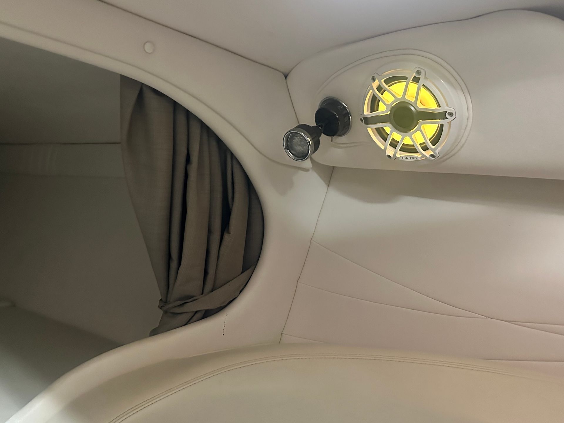 Cream-colored boat interior with speaker, light, curtain.