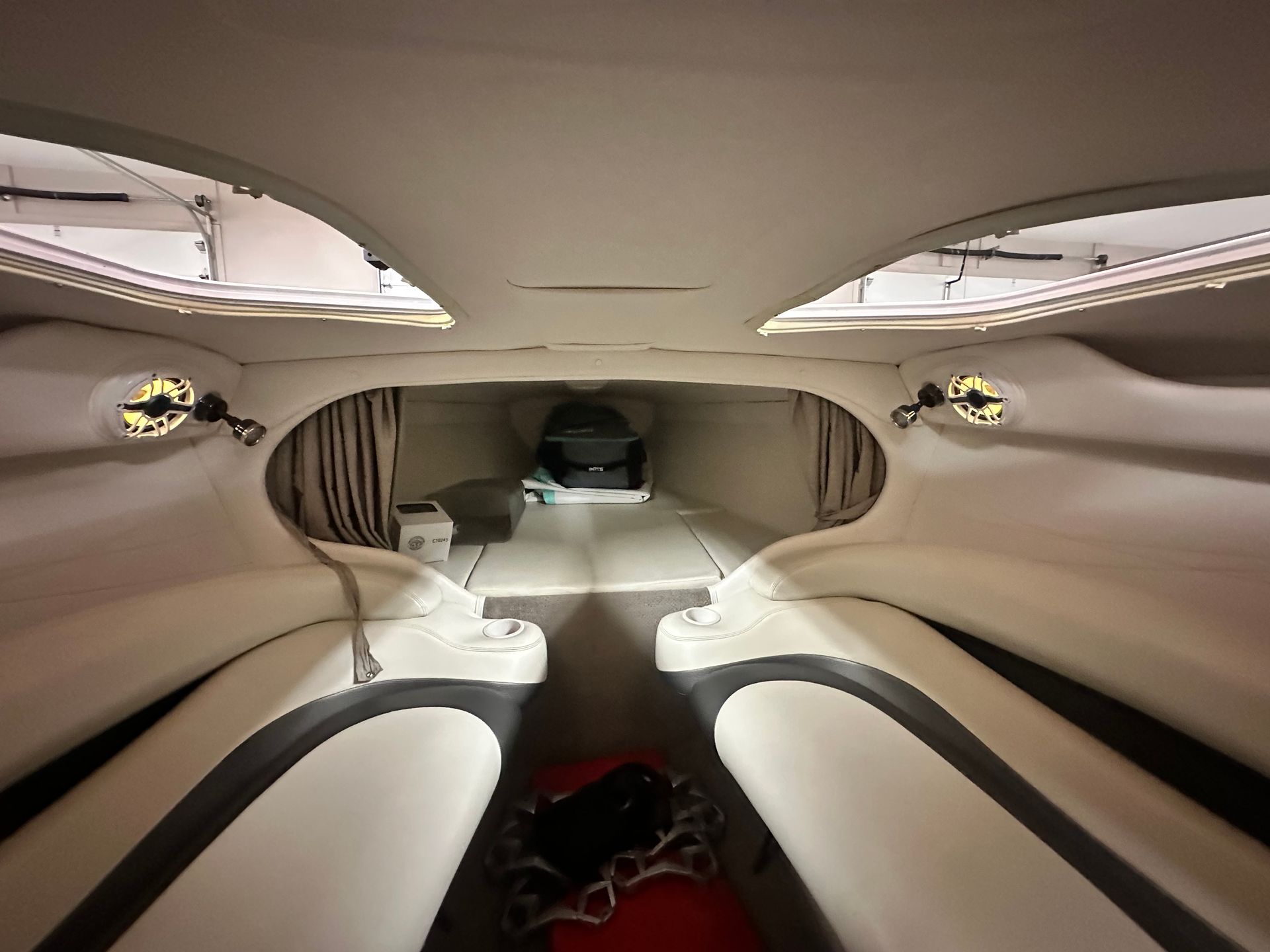 Inside the cabin of a sleek white speedboat, with seating and a long, narrow interior.