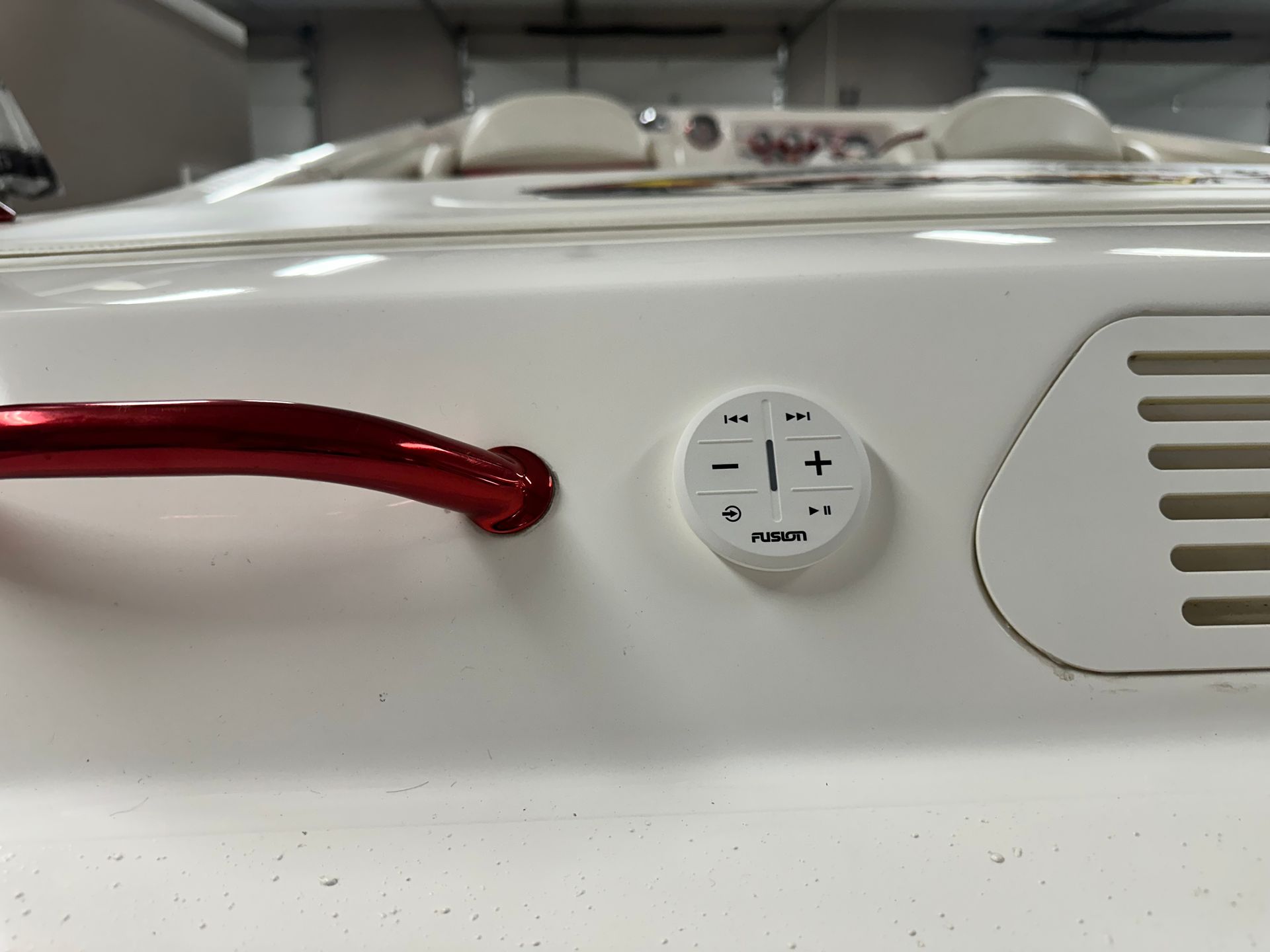 White boat stern with a red grab bar and a circular control panel.