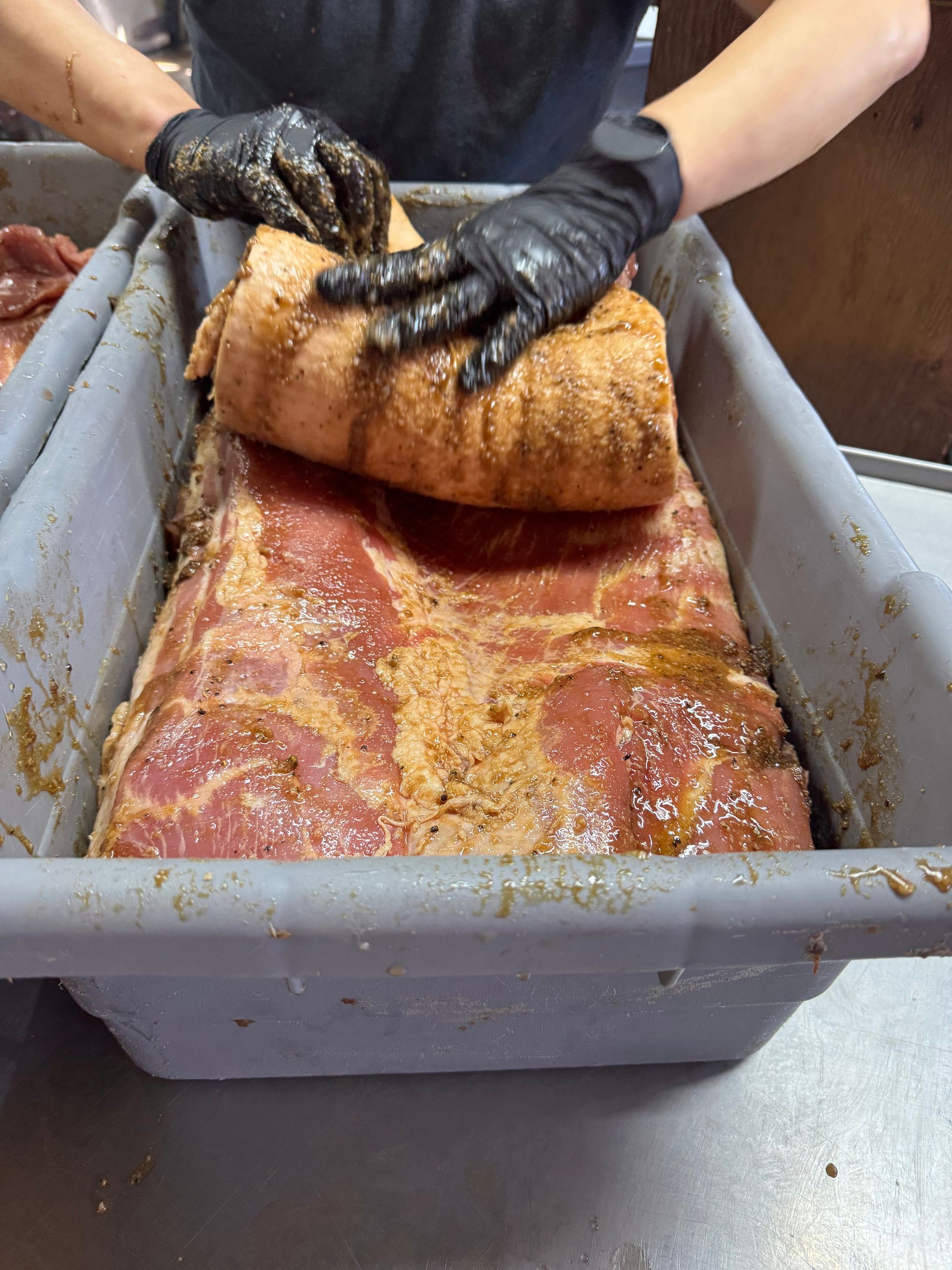 A person is holding a piece of meat in a tray.