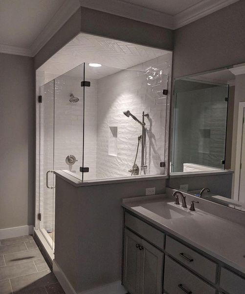 Modern bathroom featuring a glass-enclosed shower, vanity with a sink, and a large mirror. Gray walls and light countertops.