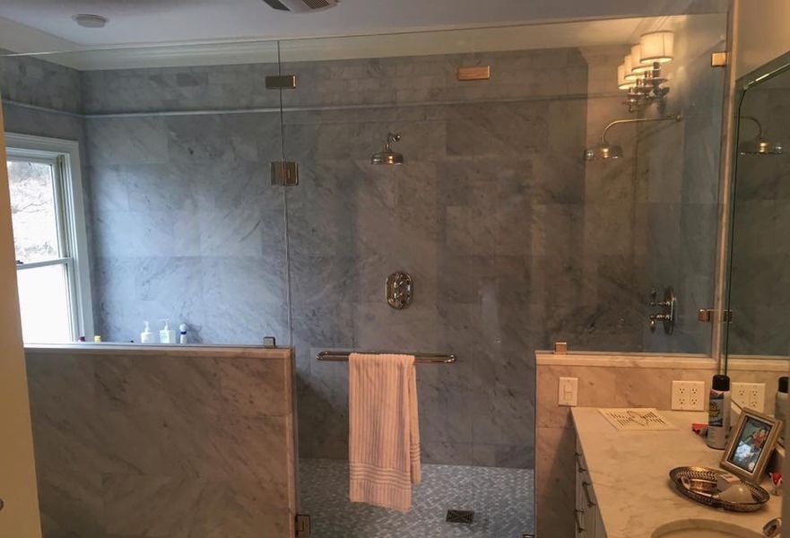 A modern bathroom with a marble tiled shower, a clear glass door, and a towel hanging on a bar.