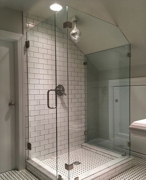 A modern glass shower enclosure with a white tiled interior, contrasting with the black and white patterned floor, and a door.