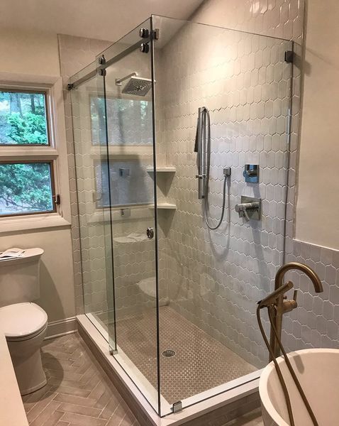 Modern bathroom with a glass shower enclosure, patterned tile walls, and a standalone tub.
