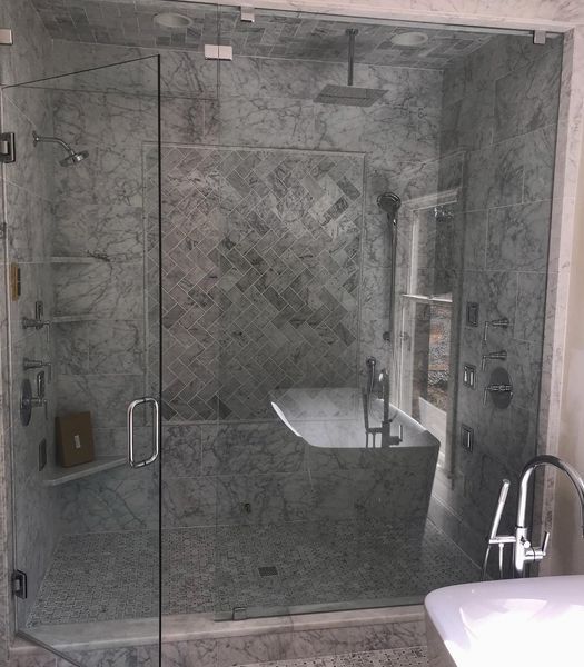 Modern bathroom with a glass-enclosed shower, a freestanding tub, and marble tile walls.