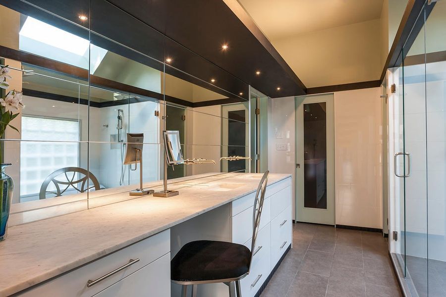 Modern bathroom with white vanity, large mirror, glass shower, and dark ceiling.
