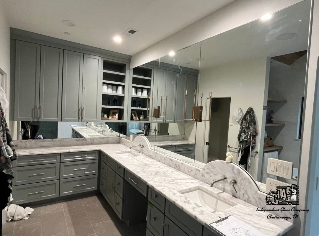 Bathroom with gray cabinets, white marble countertops, and a large mirror.