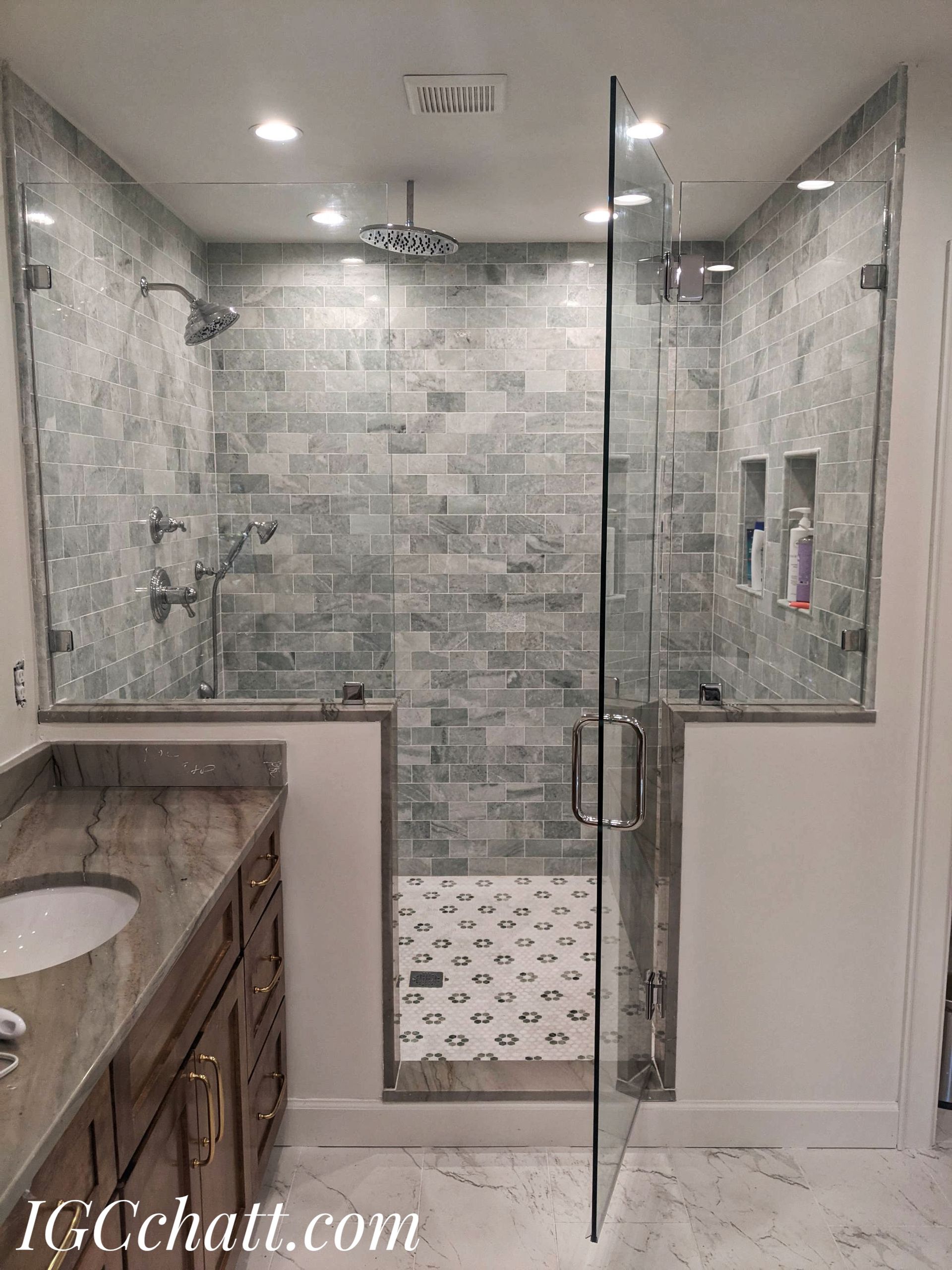 A modern bathroom featuring a tiled shower with a glass door, a double sink vanity, and marble flooring.