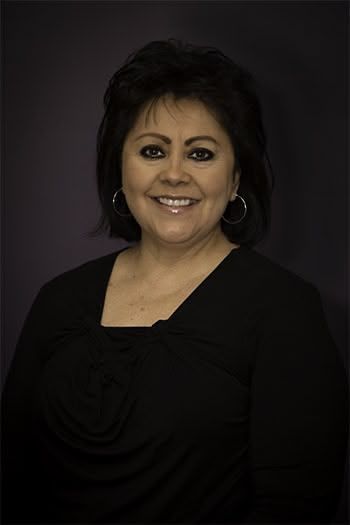 Woman with dark hair smiles, wearing a black top, against a purple background.