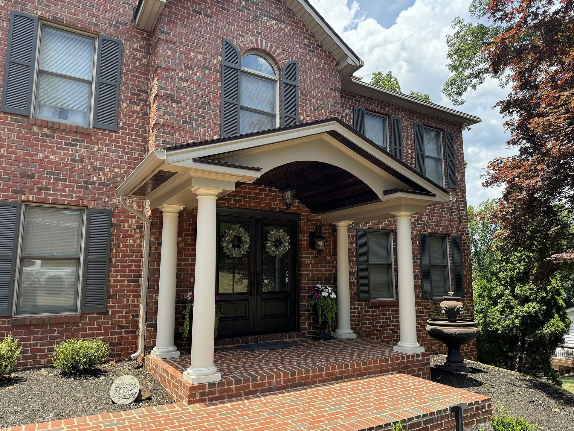 A large brick house with a porch and shutters.