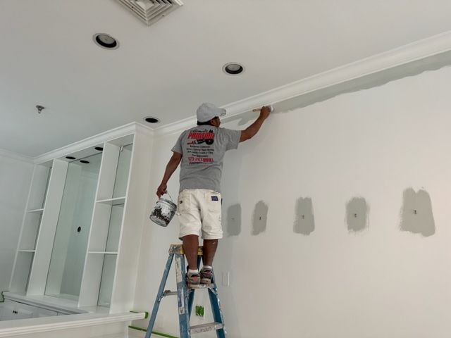 Man painting a wall with a gray paint