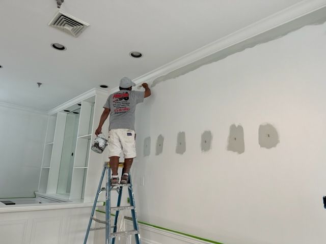 Man on a step ladder painting a wall