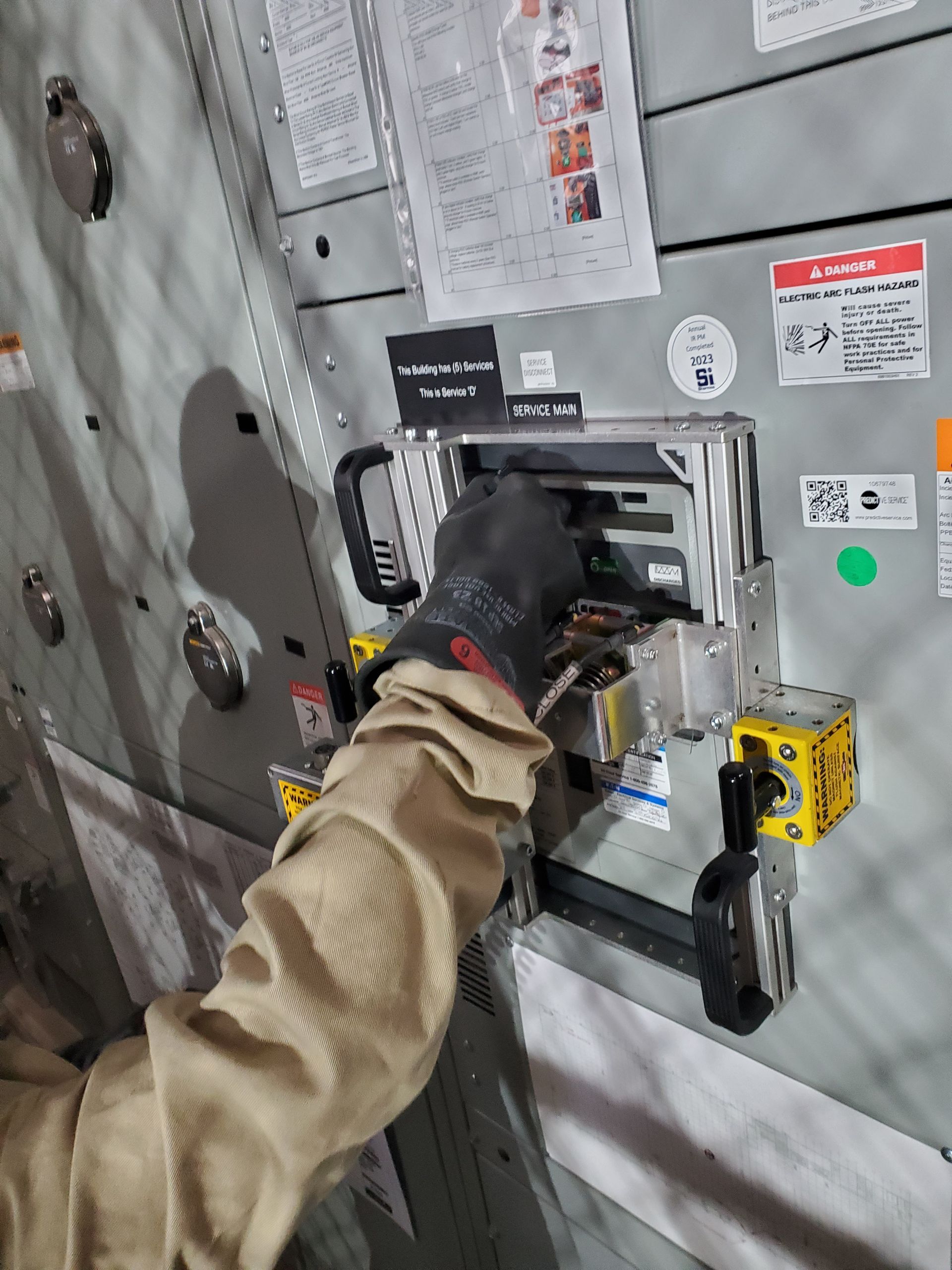 Gloved worker operating a wall-mounted industrial control panel with buttons and gauges