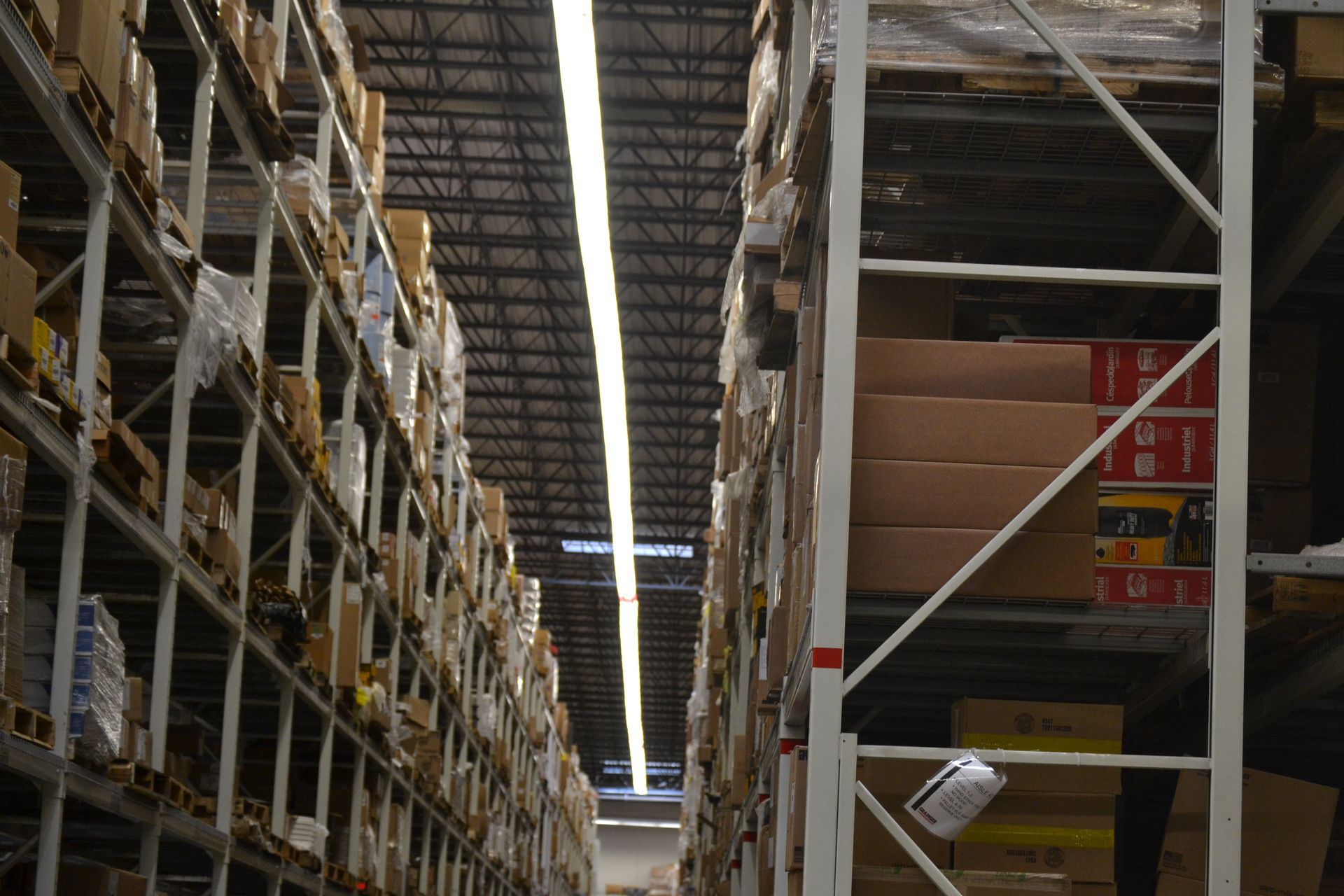 Aisle between tall warehouse shelves stacked with boxes and storage items.