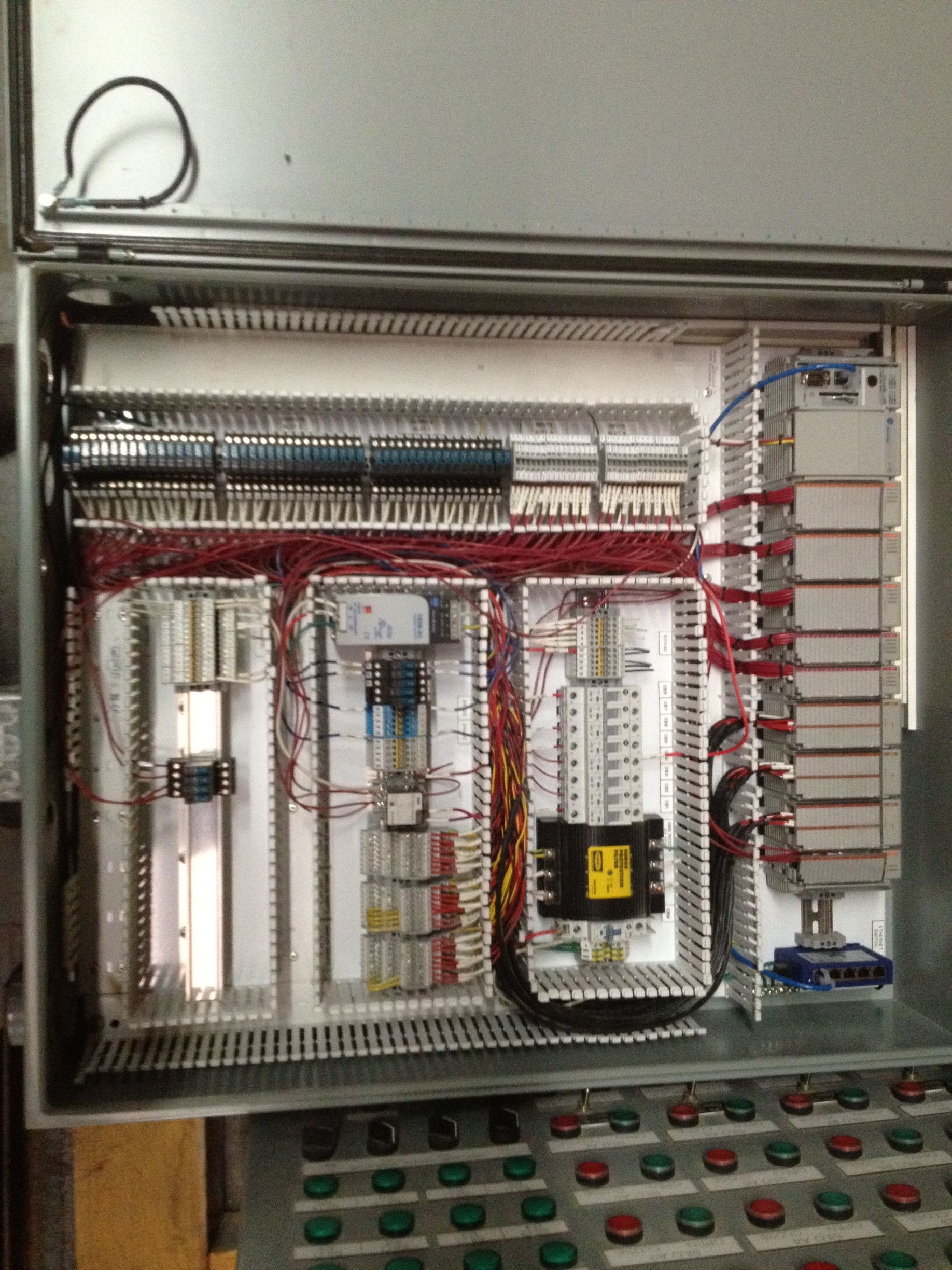 Electrical control panel with wiring, relays, and switches inside a metal enclosure