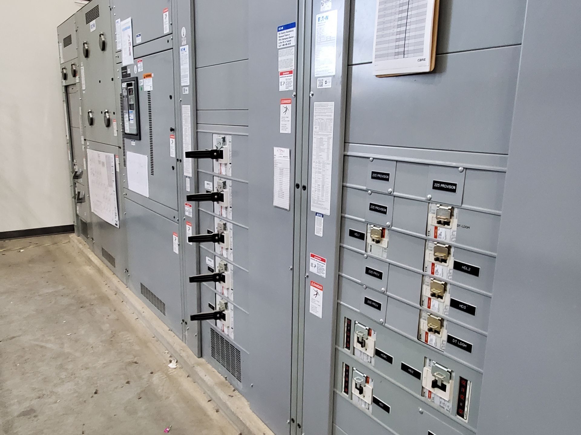 Electrical control panels and breaker cabinets in a gray industrial room with a concrete floor