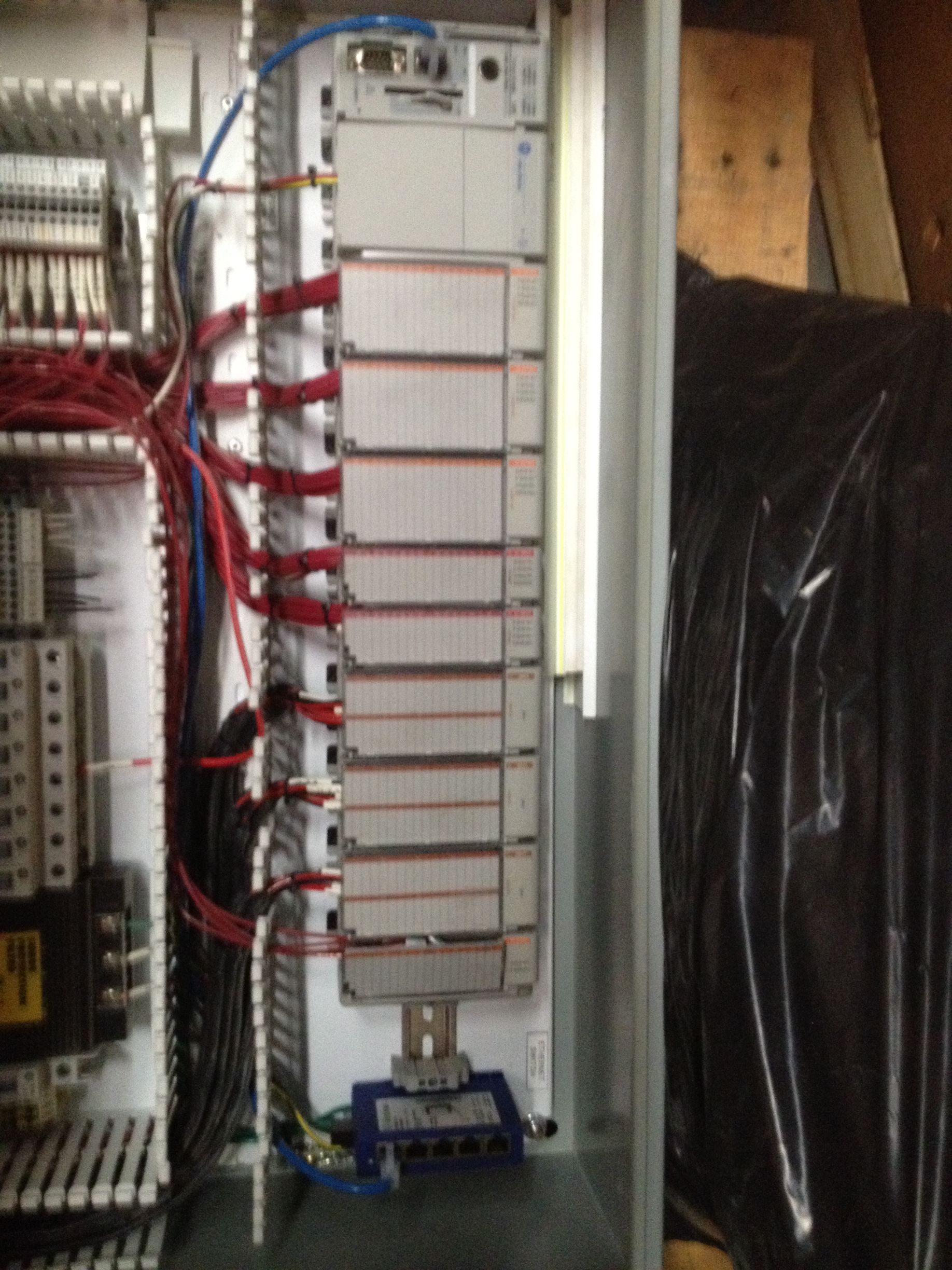 Electrical control panel with rows of modules and red wiring inside a cabinet