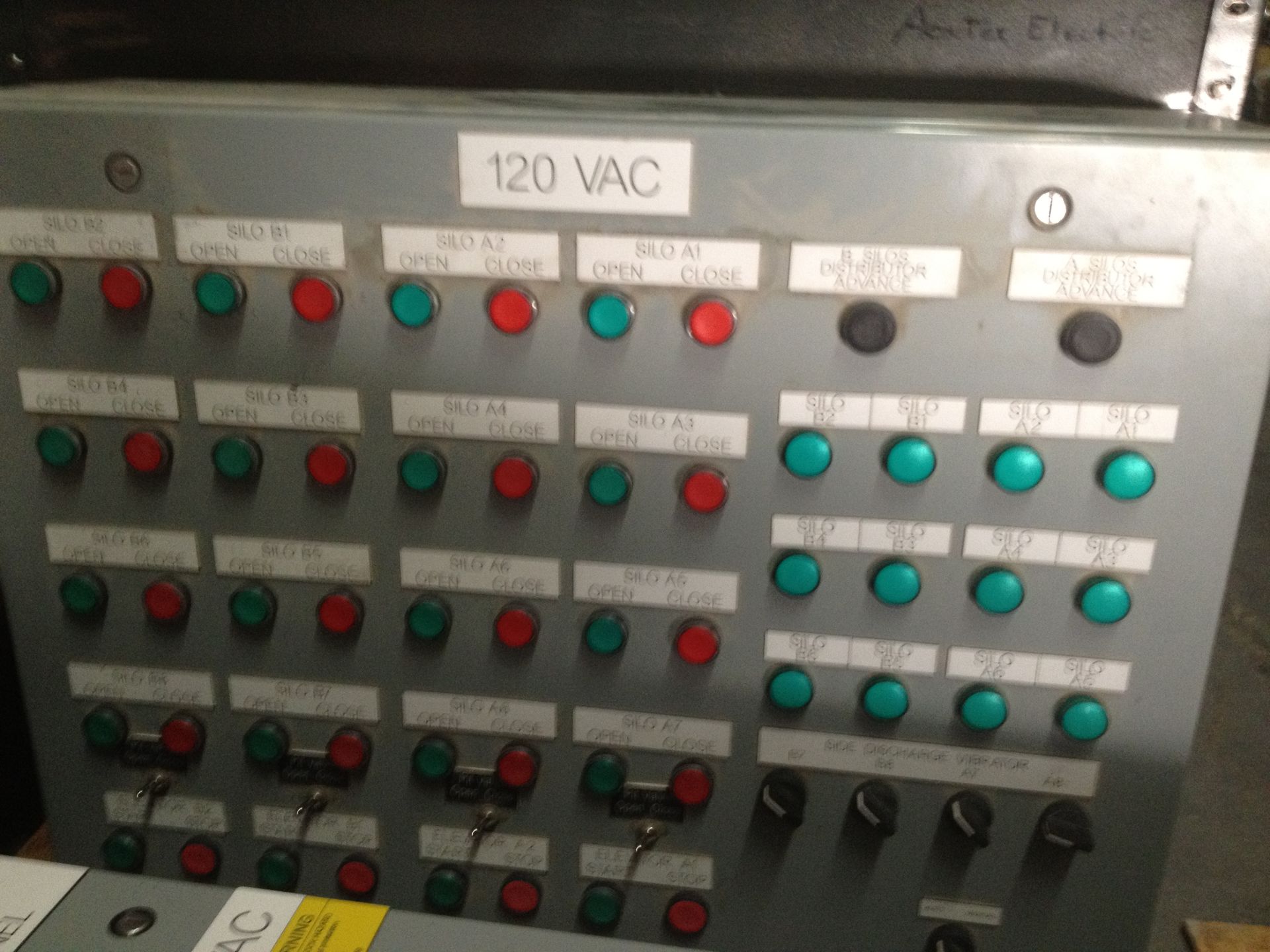 Electrical control panel with rows of red, green, and blue buttons labeled 120 VAC