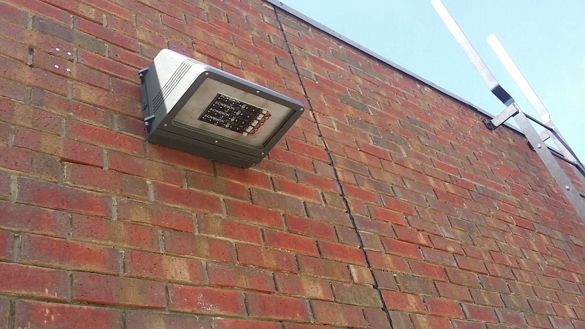 Wall-mounted exterior light fixture on a red brick building.