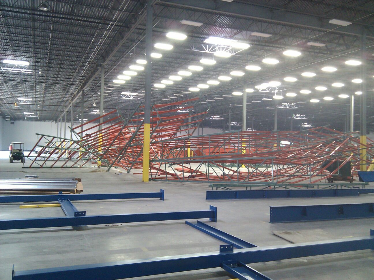 Collapsed red warehouse racking inside a large industrial storage facility